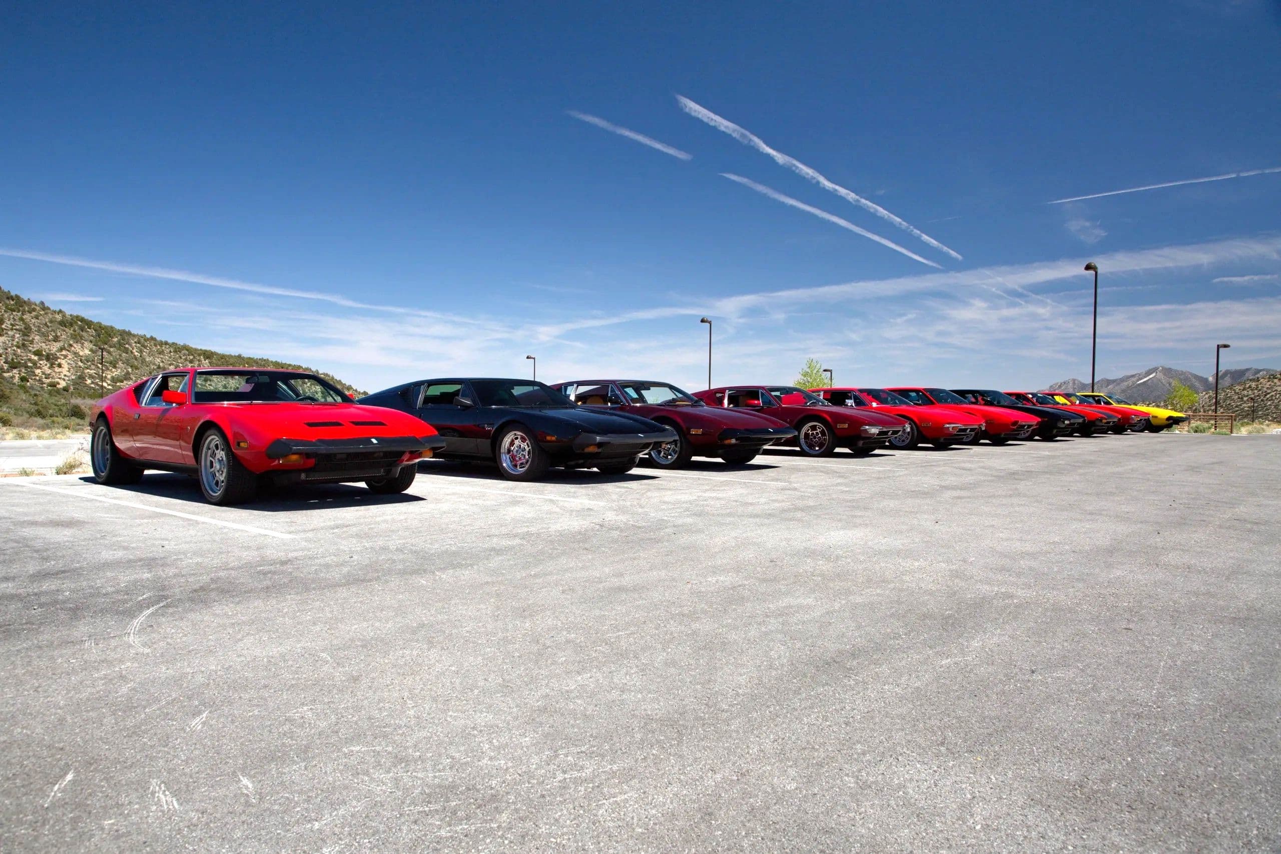 A row of DeTomaso Panteras lined up against a mountain backdrop